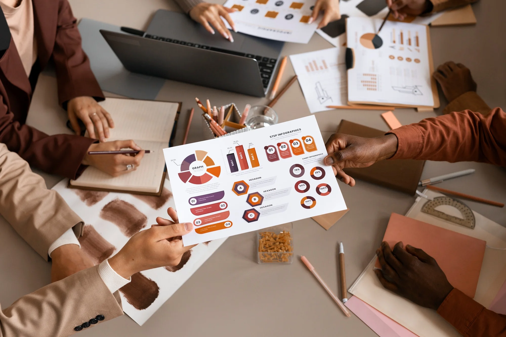 A top-down view of a diverse professional team collaborating at a desk, with one person handing over a sheet of infographic charts and financial data analytics.